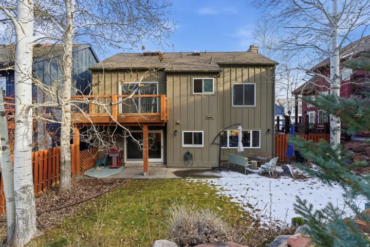 Back of house with board and batten siding, a patio area, roof with shingles, and a chimney