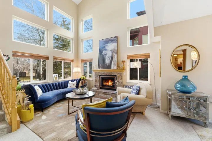 Living area with a fireplace, carpet, healthy amount of natural light, and a high ceiling