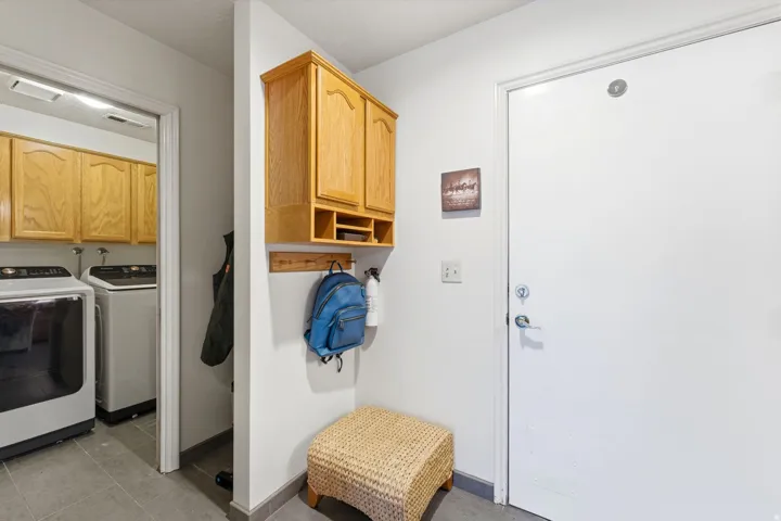 Laundry area with separate washer and dryer, cabinet space, and light tile patterned floors