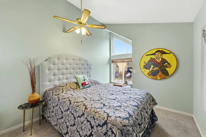 Carpeted bedroom with vaulted ceiling and ceiling fan