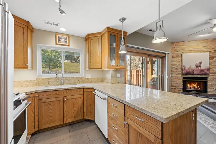 Kitchen featuring decorative light fixtures, wood finish cabinetry, glass fronted cabinets, open floor plan, and light stone counters