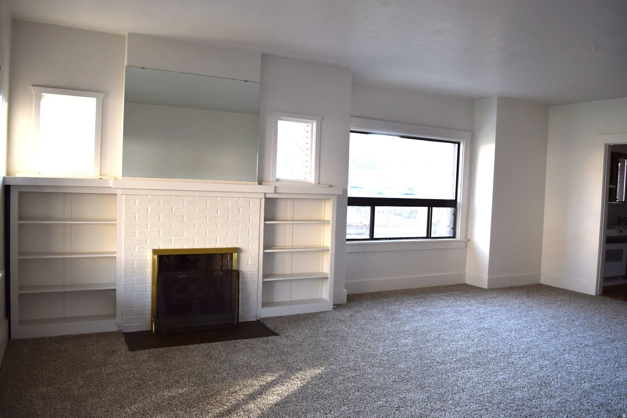 Unfurnished living room with carpet flooring and a brick fireplace