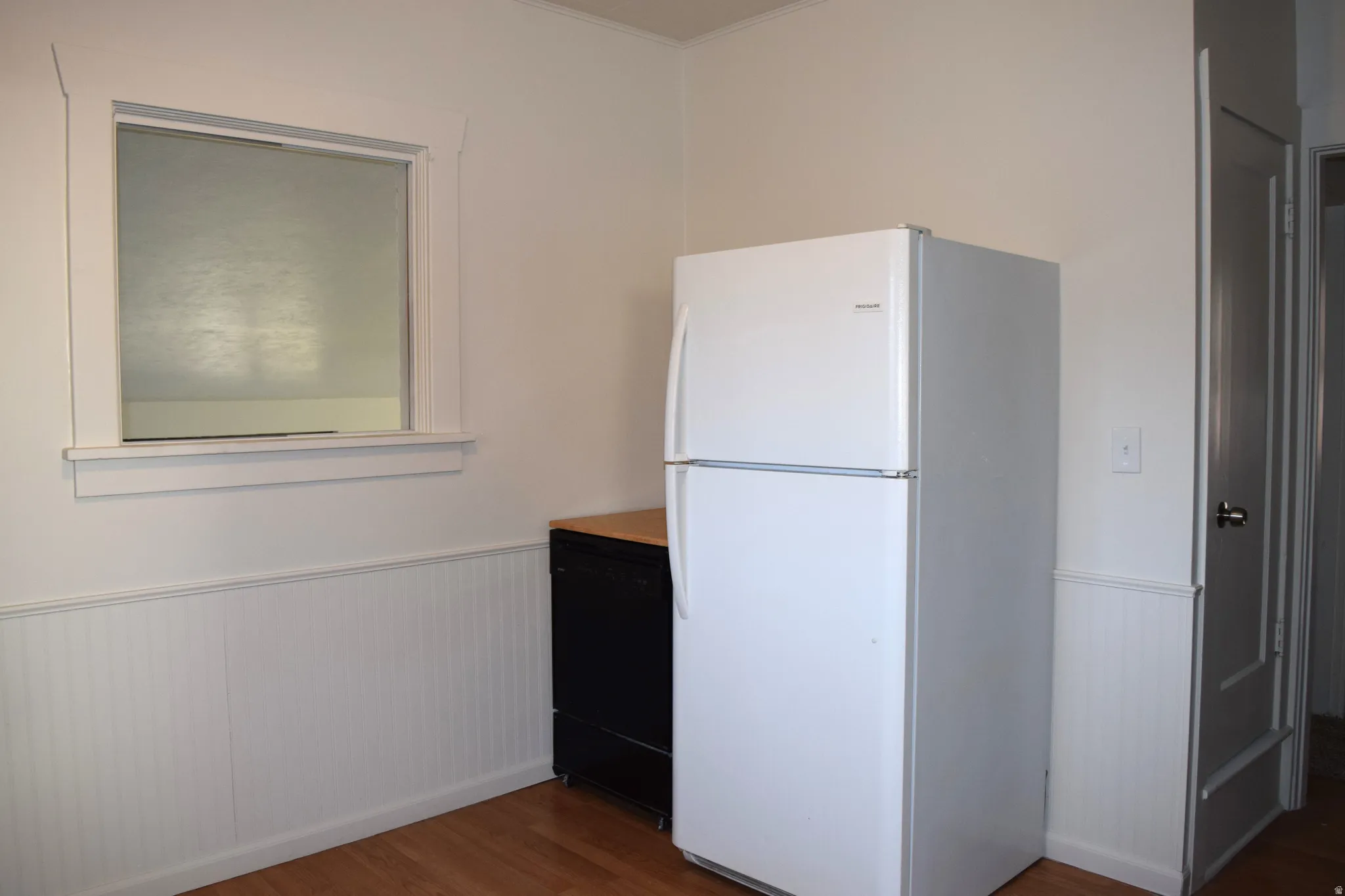 Kitchen with wainscoting, freestanding refrigerator, dark wood finished floors, and dishwasher