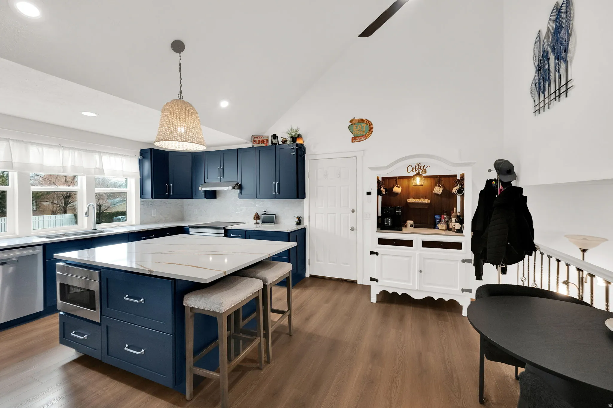 Kitchen featuring blue cabinets, a kitchen bar, wood finished floors, stainless steel appliances, and a center island
