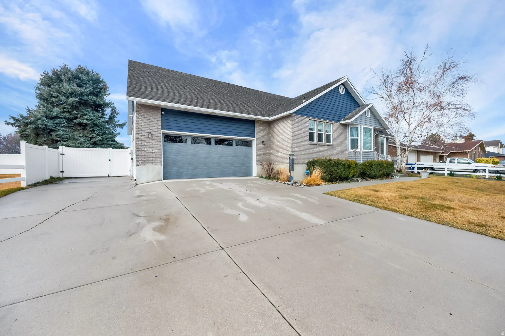 Ranch-style house featuring a gate, brick siding, concrete driveway, and a shingled roof