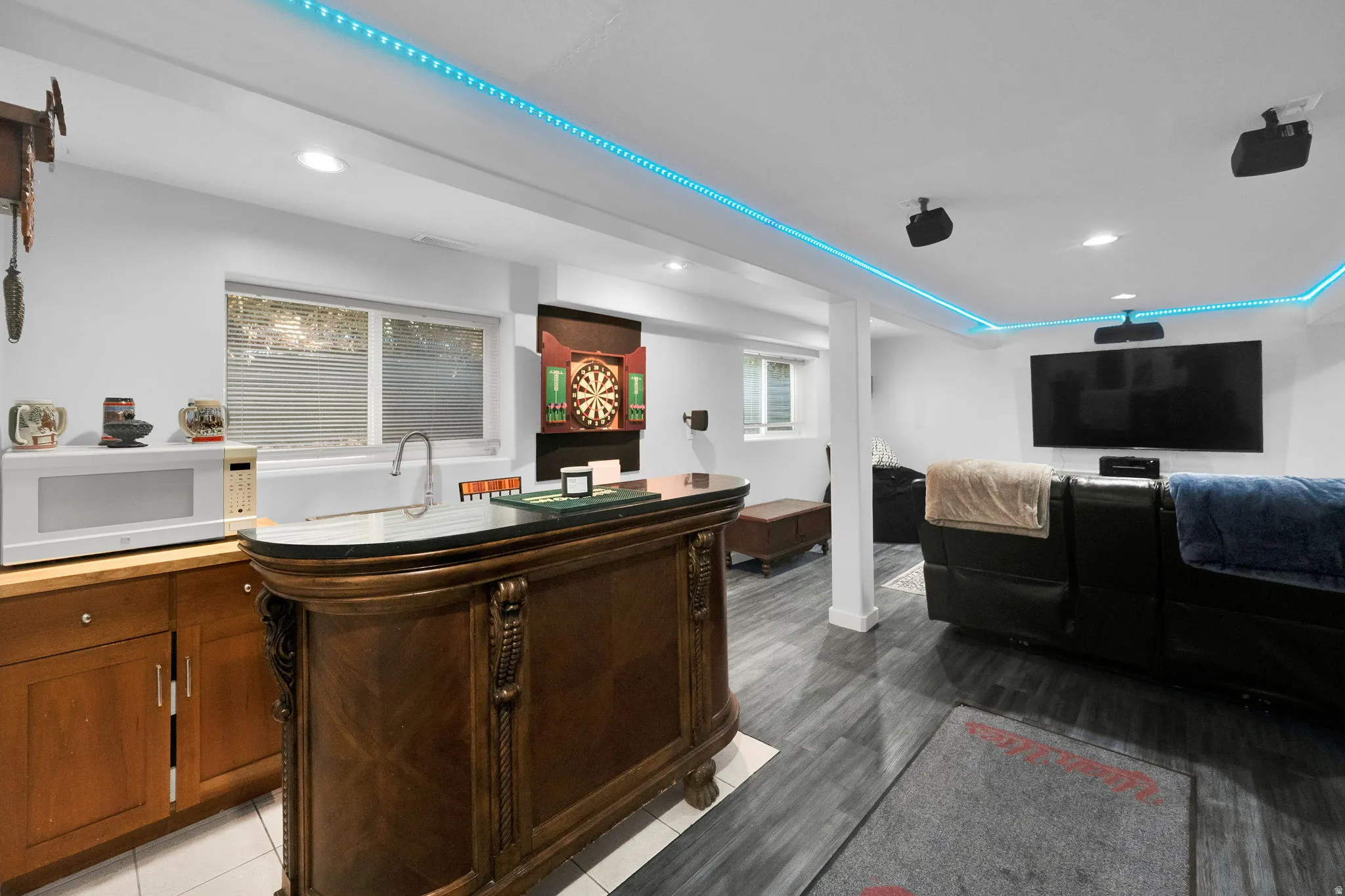 Indoor wet bar featuring white microwave, recessed lighting, light wood-type flooring, and light countertops