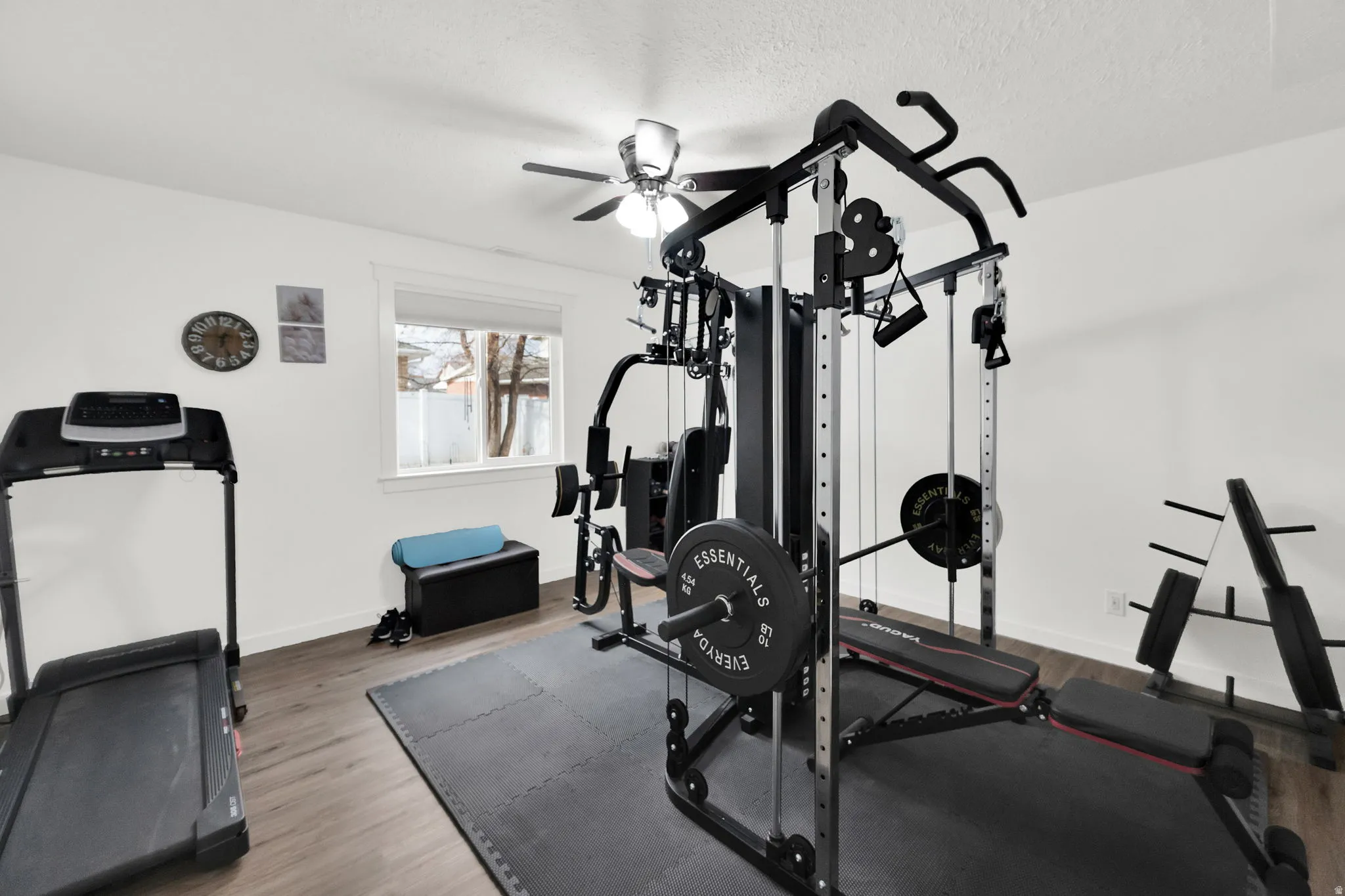 Exercise room with wood finished floors, ceiling fan, and a textured ceiling