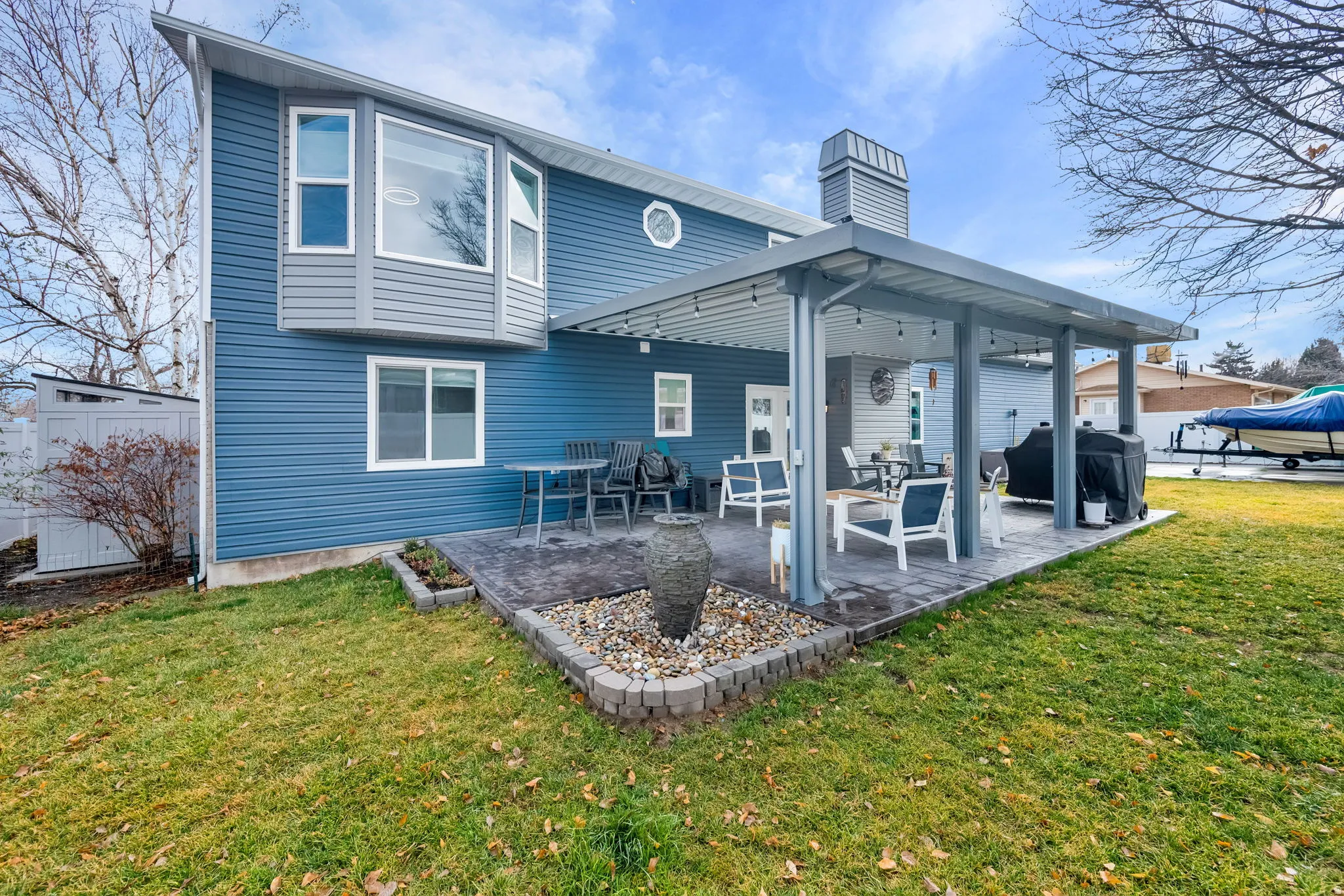 Back of house featuring a lawn, a chimney, and a patio area