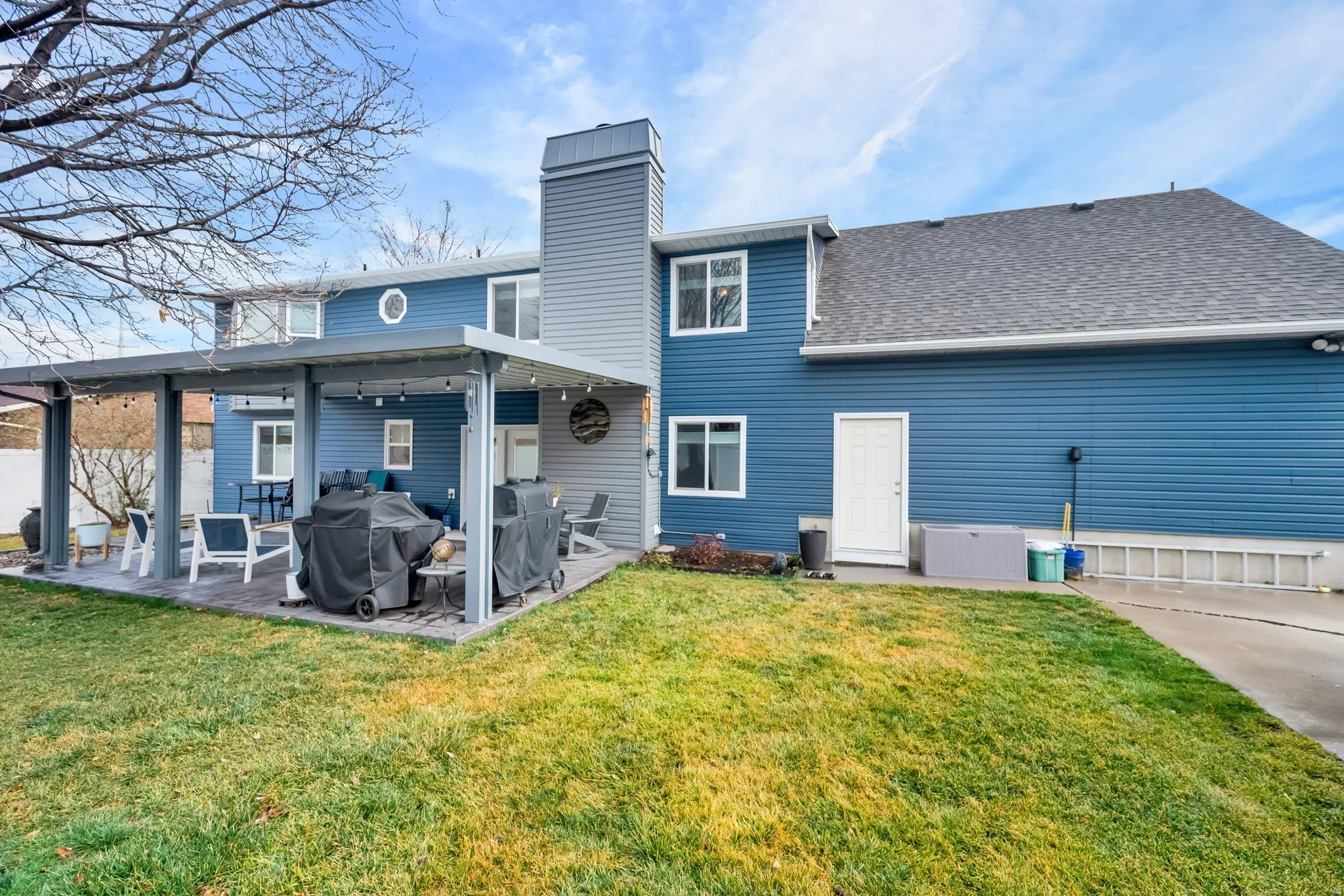 Back of property with roof with shingles, a patio, and a chimney