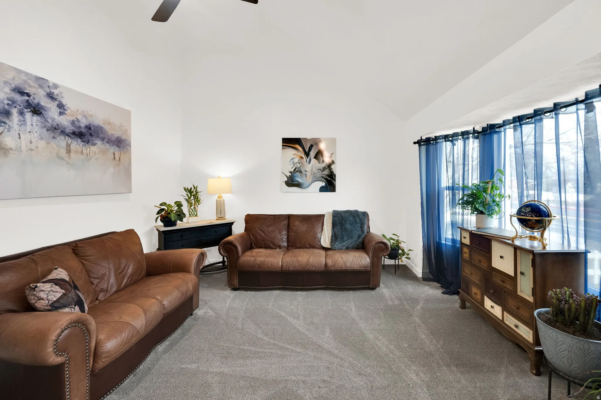 Carpeted living room featuring vaulted ceiling and a ceiling fan