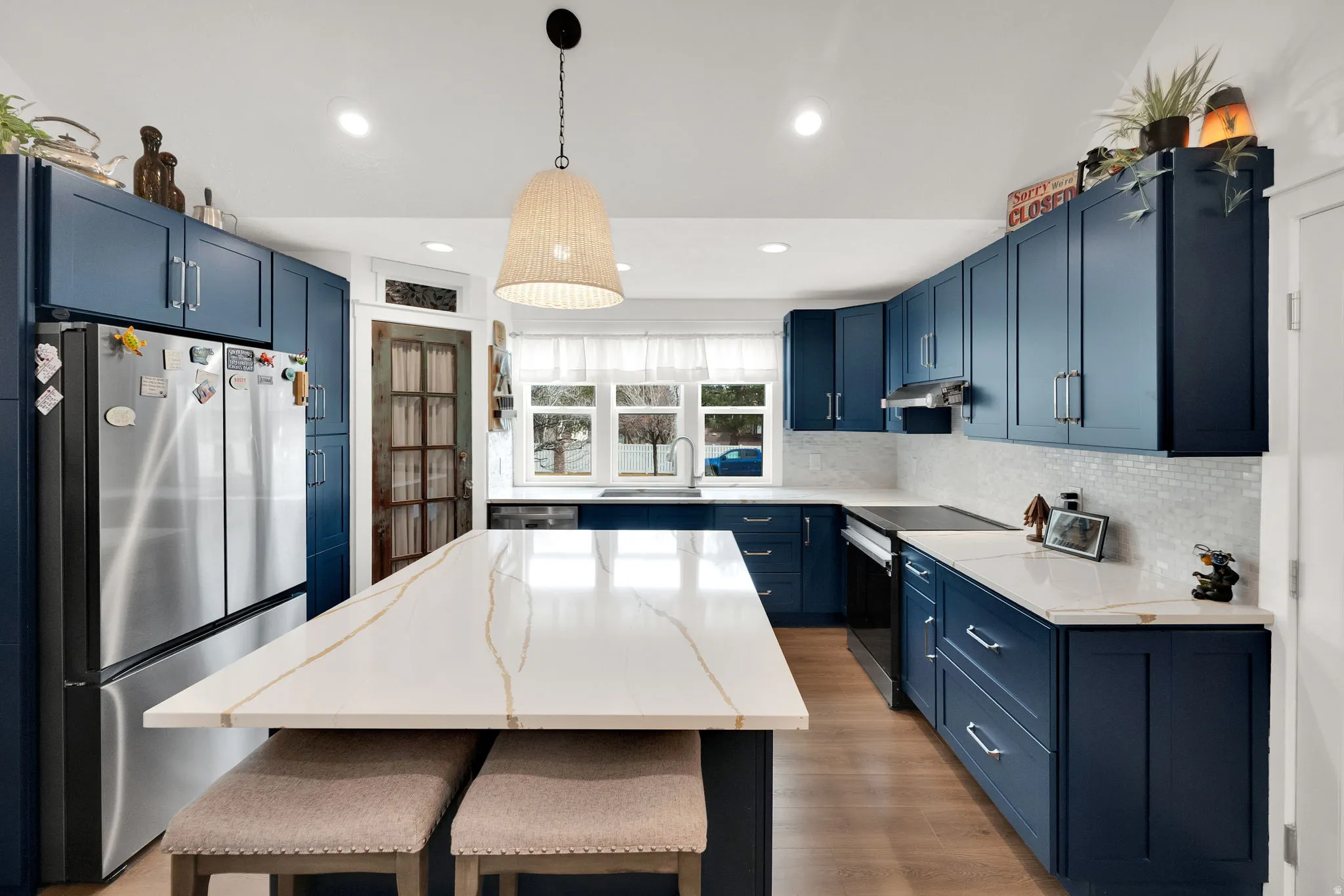 Kitchen featuring blue cabinets, pendant lighting, freestanding refrigerator, a center island, and electric stove