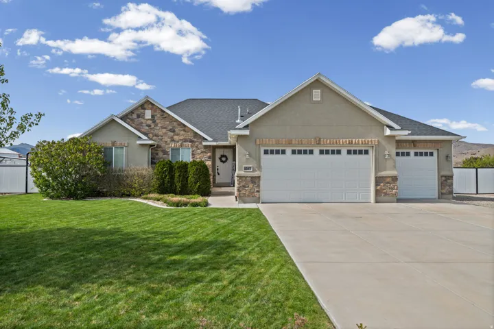 Craftsman-style house with a garage, concrete driveway, a front yard, stone siding, and roof with shingles