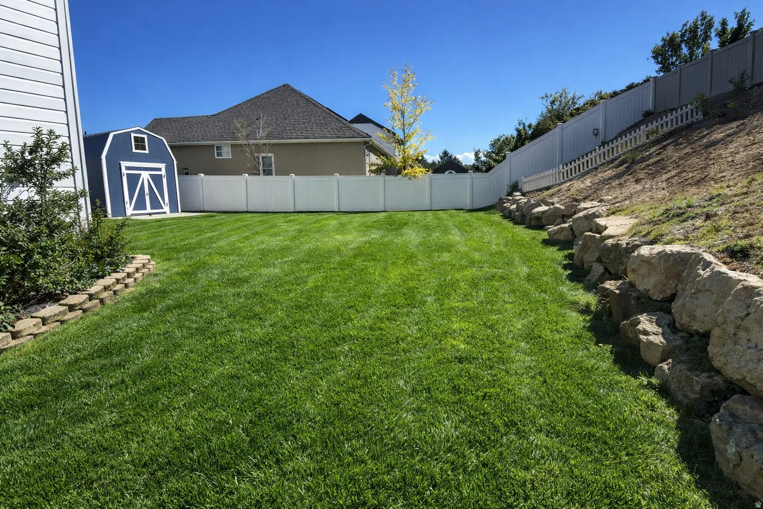 Fenced backyard featuring a shed, summer photo of backyard