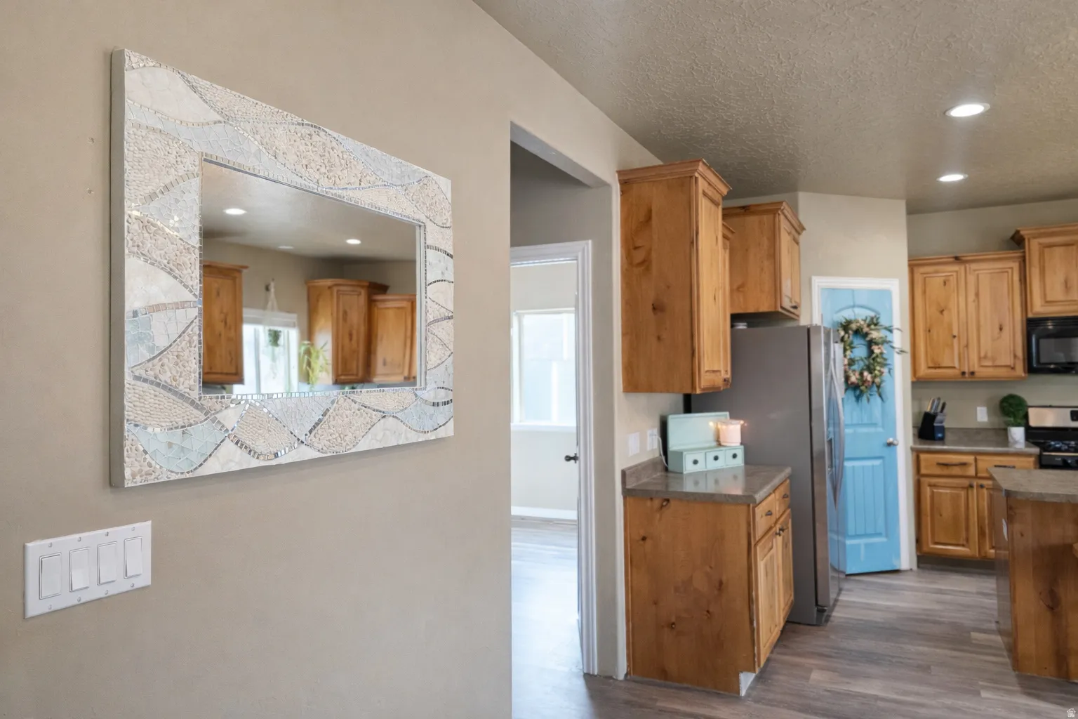 Kitchen with recessed lighting, stainless steel appliances, a textured ceiling, dark wood-type flooring, and wood finish cabinetry