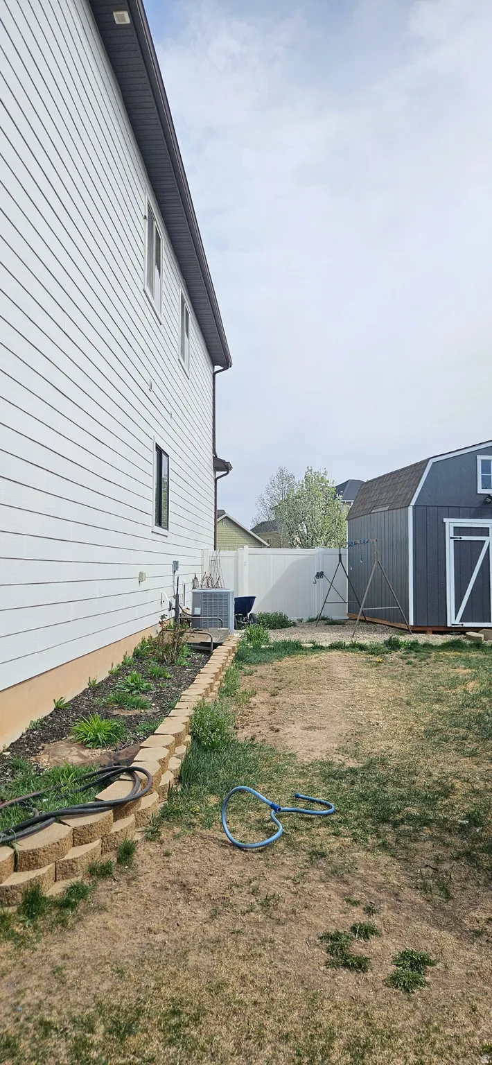 Fenced backyard featuring an outbuilding
