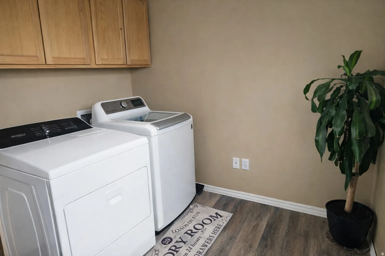 Laundry room featuring washer and dryer, dark wood finished floors, and cabinet space