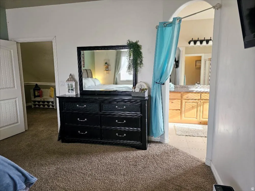 Bedroom featuring light colored carpet and ensuite bath