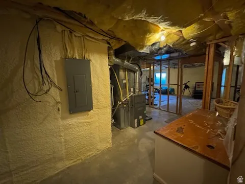 Unfinished below grade area with electric panel and heating unit