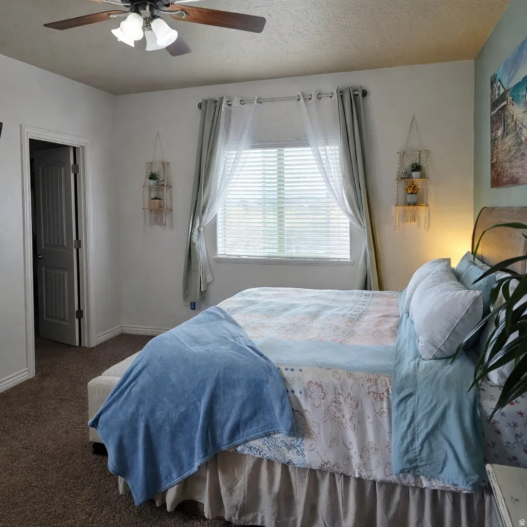 Carpeted bedroom with a textured ceiling and ceiling fan