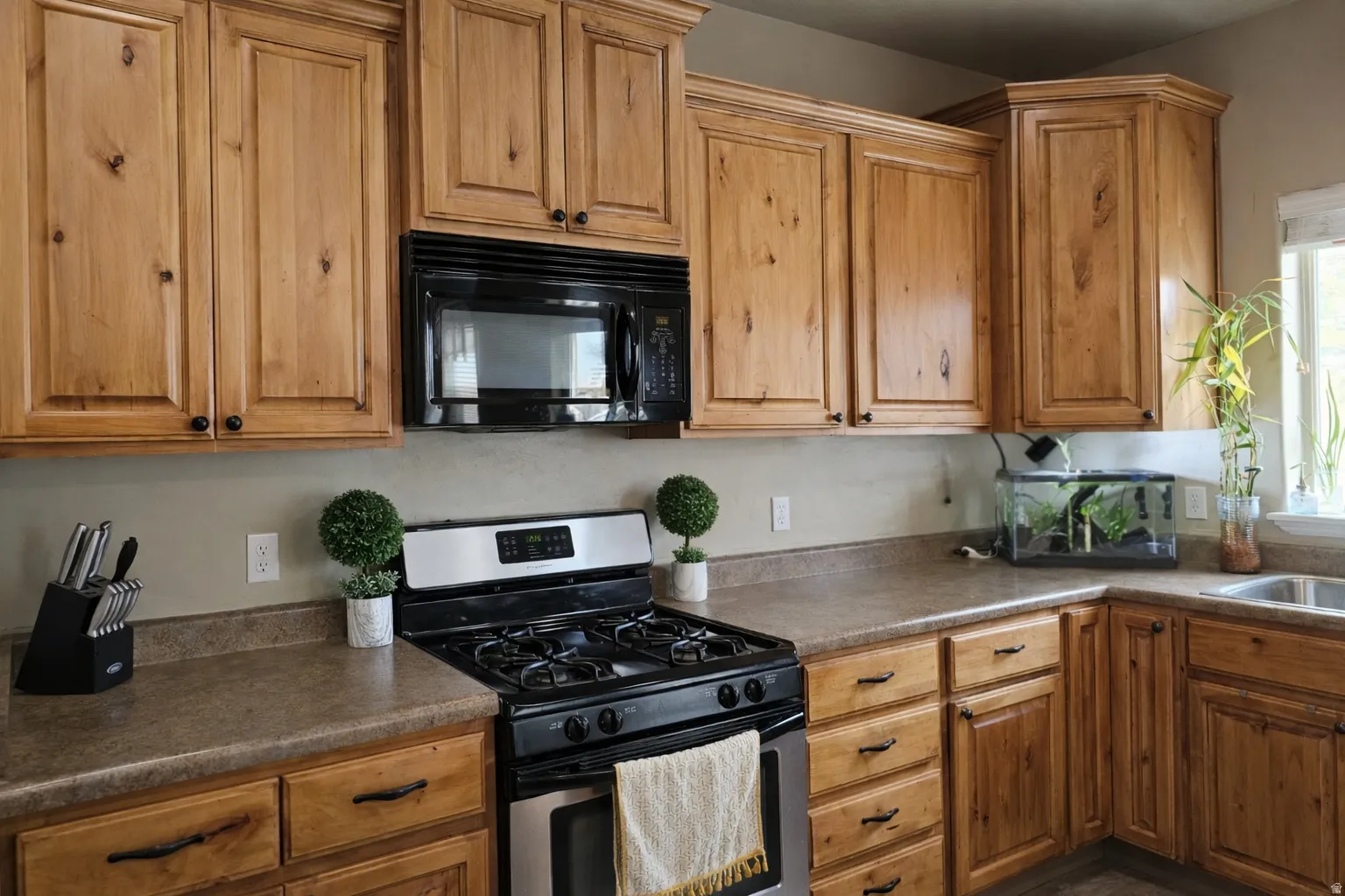Kitchen featuring stainless steel gas range, black microwave, dark countertops, and wood finish cabinetry