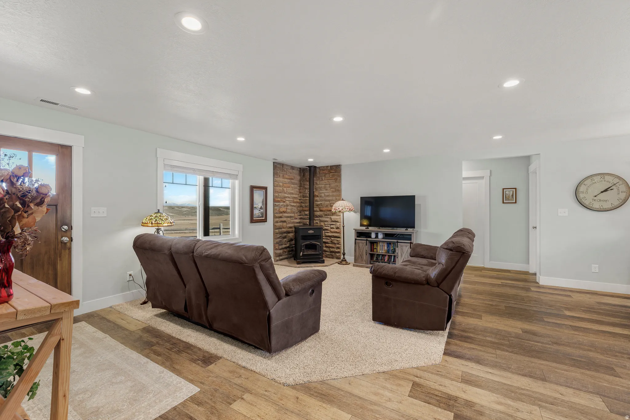Living room with wood finished floors, a wood stove, and recessed lighting