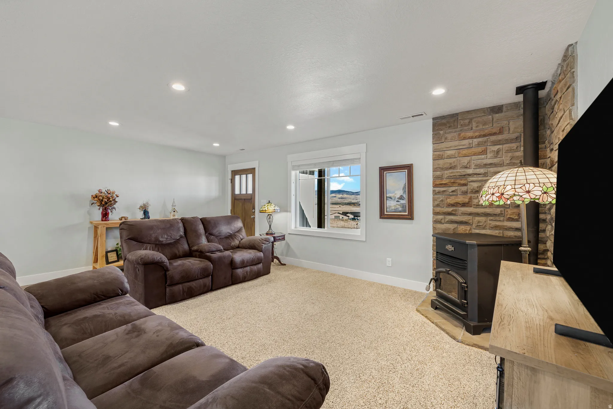 Living room with a wood stove, light colored carpet, and recessed lighting