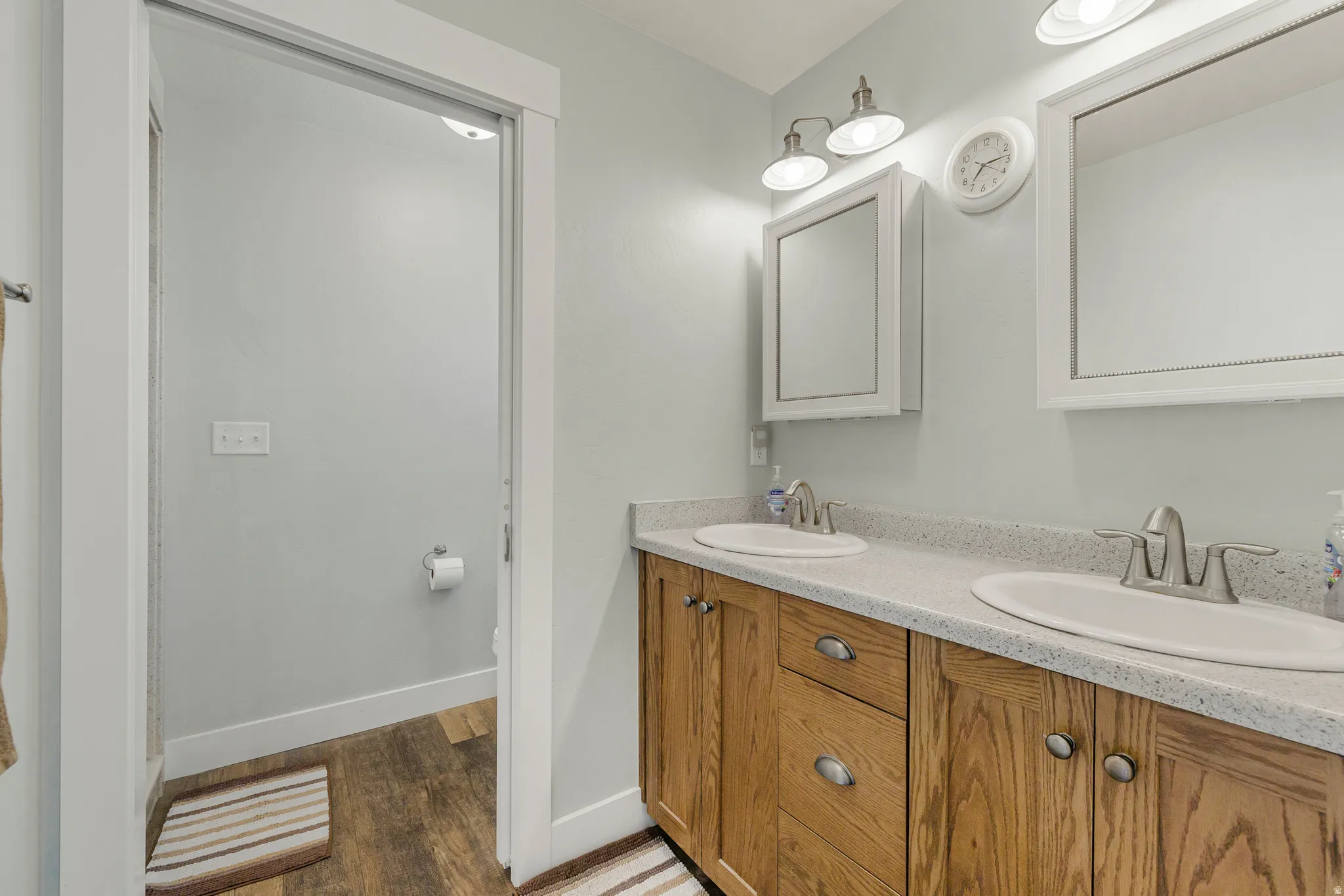 Full bathroom featuring double vanity and dark wood finished floors
