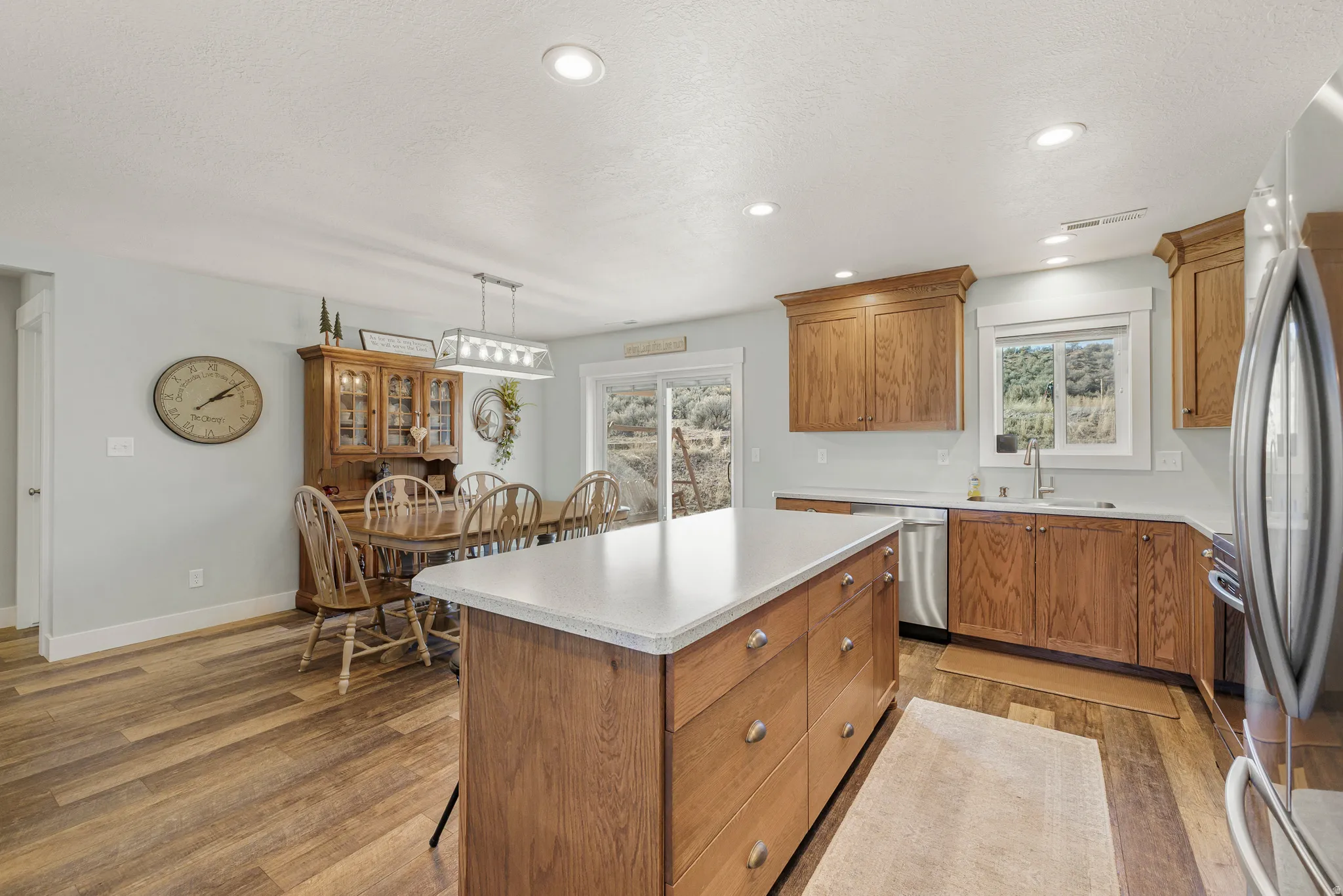 Kitchen featuring wood finish cabinetry, a center island, stainless steel appliances, light countertops, and a textured ceiling