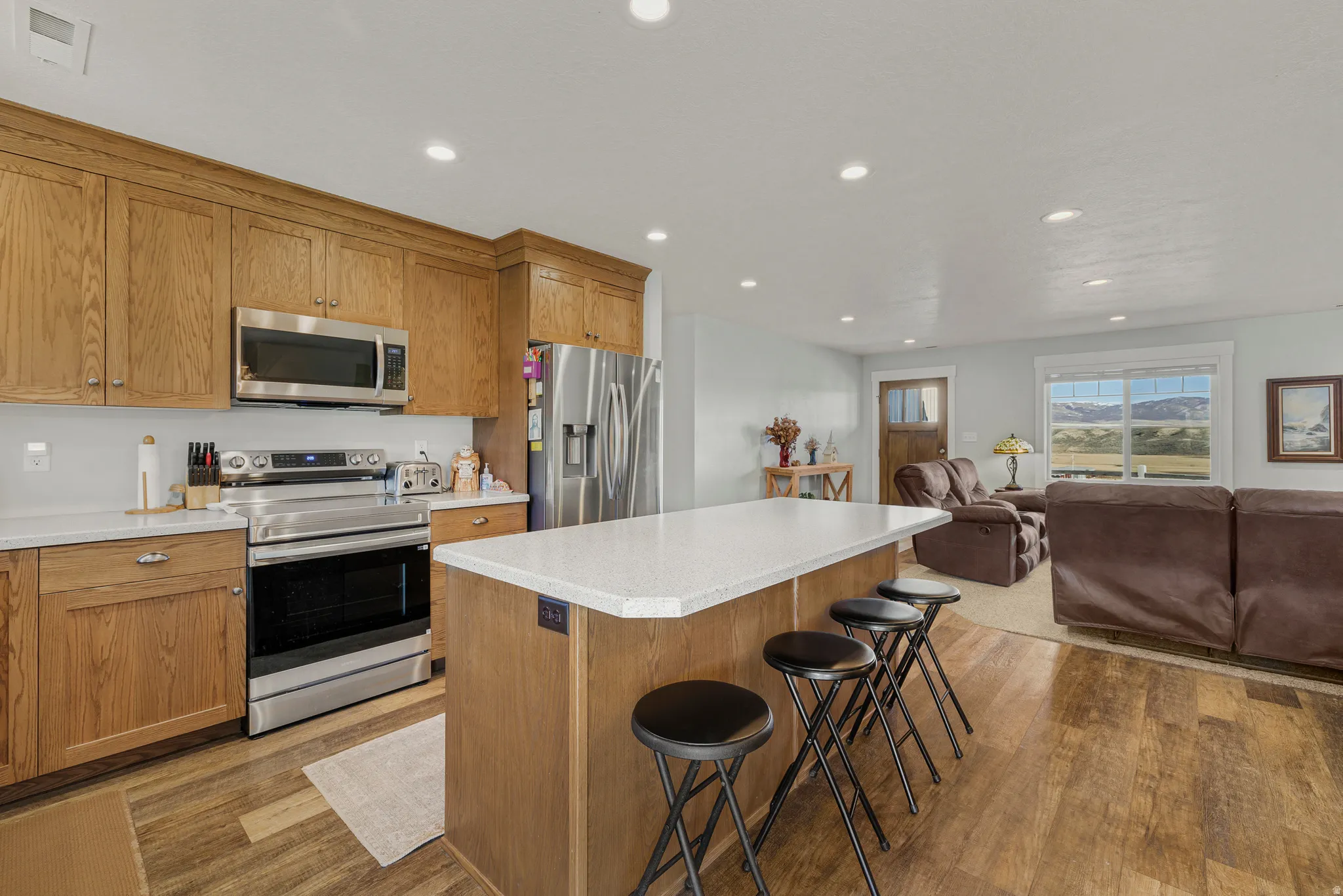 Kitchen with stainless steel appliances, a breakfast bar, light wood-style floors, recessed lighting, and open floor plan