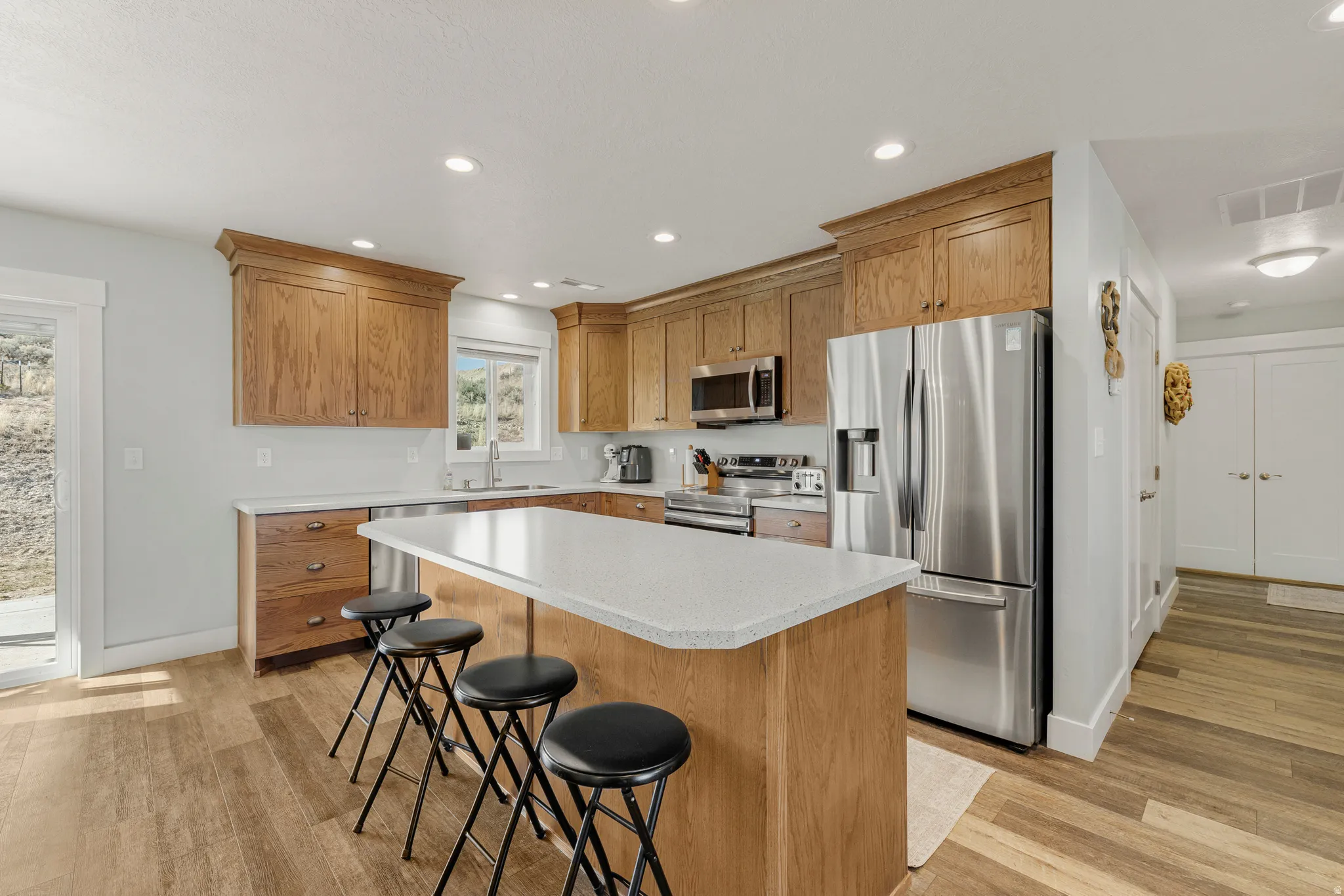 Kitchen with stainless steel appliances, recessed lighting, a breakfast bar area, a kitchen island, and light wood-type flooring