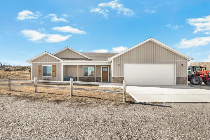 Ranch-style home featuring concrete driveway, covered porch, stone siding, a garage, and roof with shingles