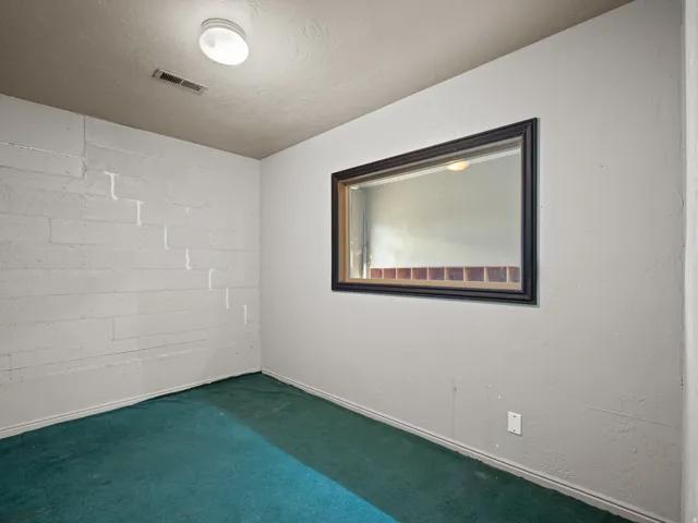 Unfurnished room with concrete block wall, carpet flooring, and a textured ceiling