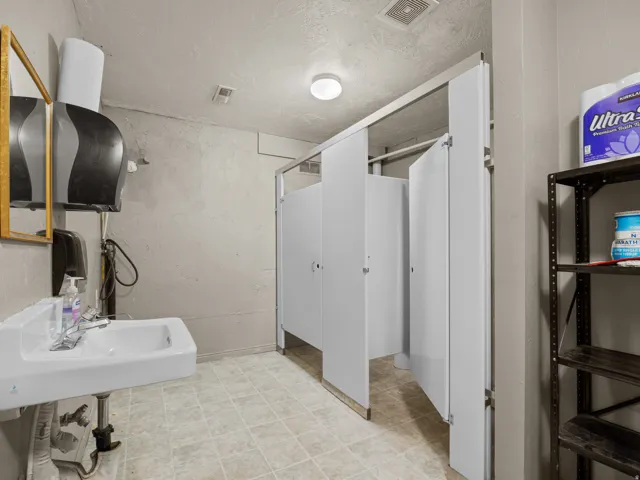 Bathroom with a textured wall, a textured ceiling, and light floors