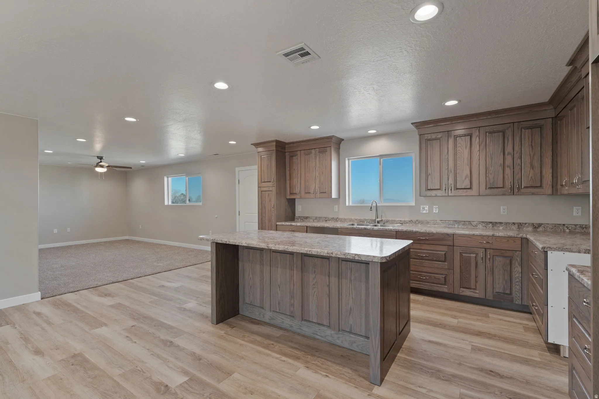 Kitchen featuring a kitchen island, open floor plan, recessed lighting, ceiling fan, and light wood-style floors