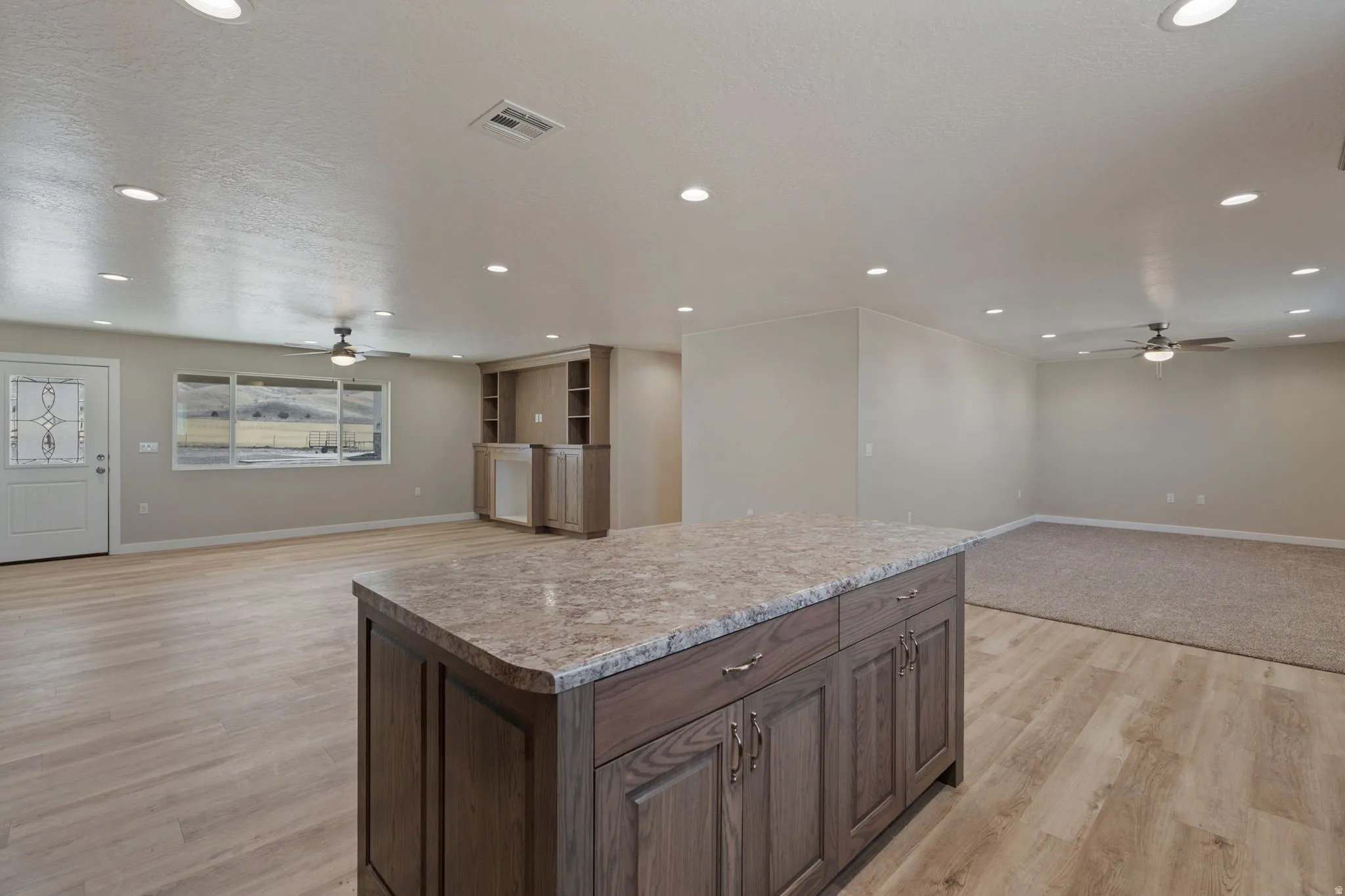 Kitchen with a ceiling fan, open floor plan, a kitchen island, dark wood finish cabinets, and recessed lighting