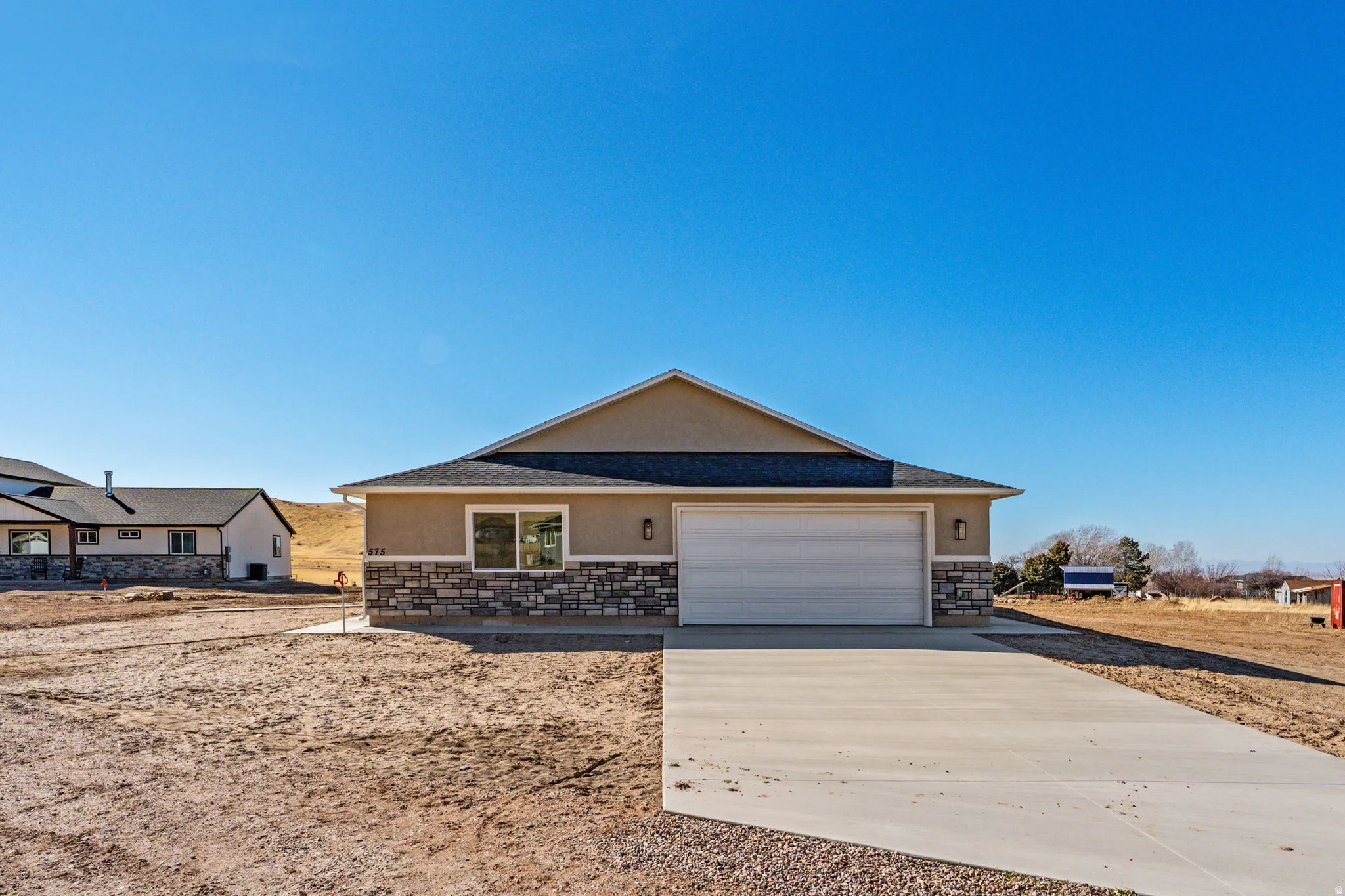 Ranch-style home with stone siding, stucco siding, driveway, and a garage