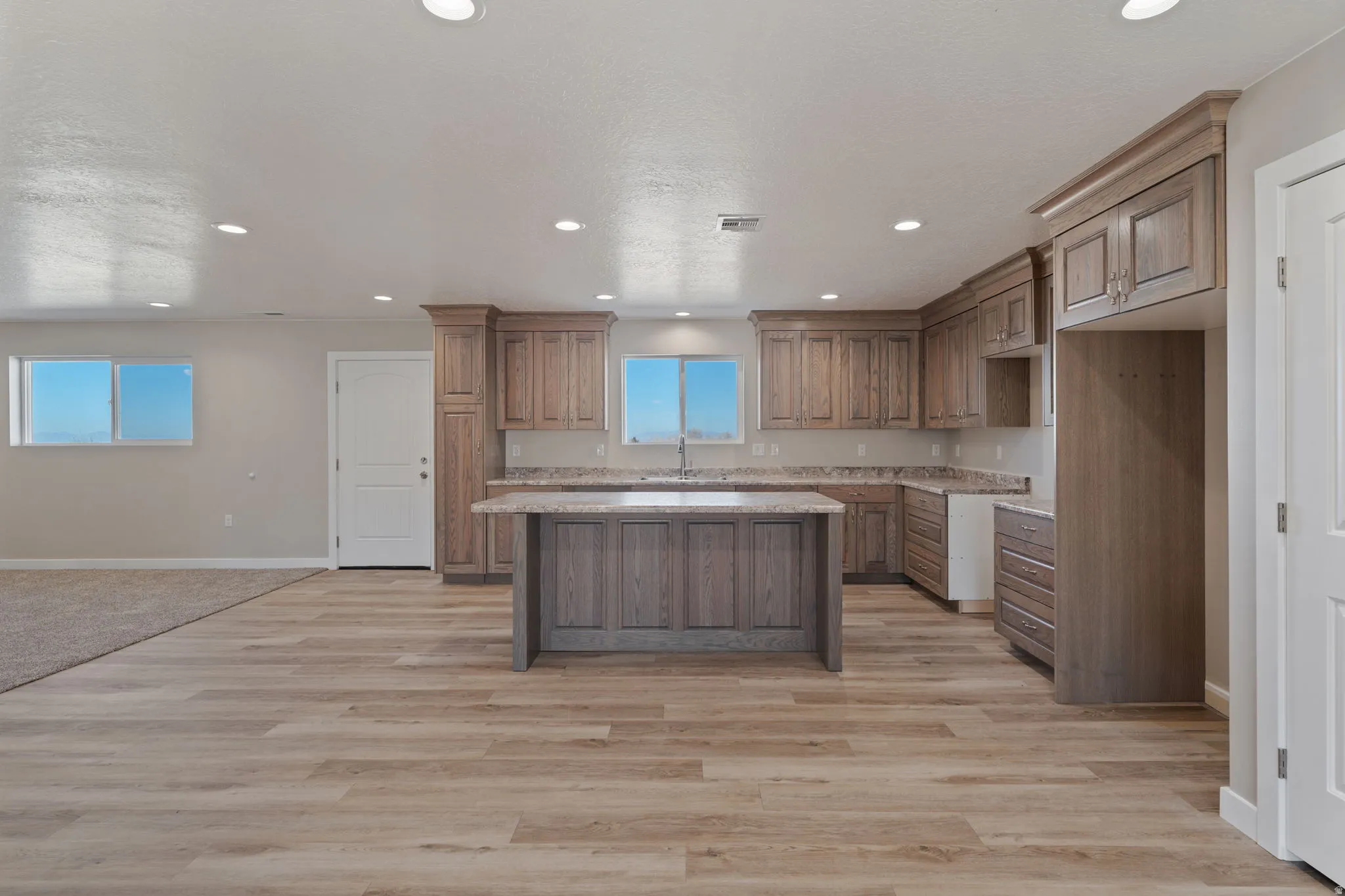Kitchen with a center island, wood finish cabinetry, open floor plan, light wood-style flooring, and recessed lighting