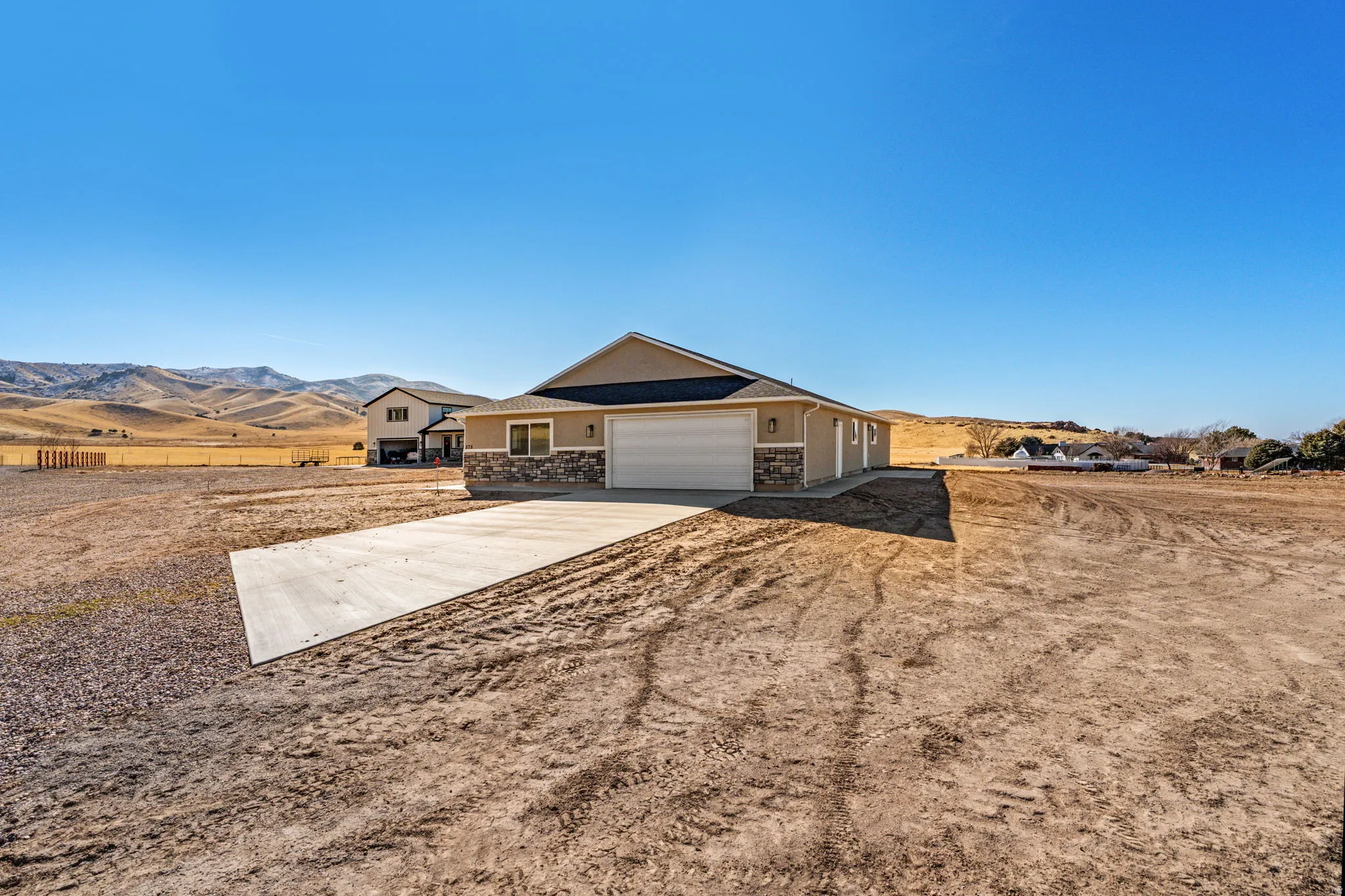 Ranch-style home featuring a mountain view, concrete driveway, stone siding, and a garage