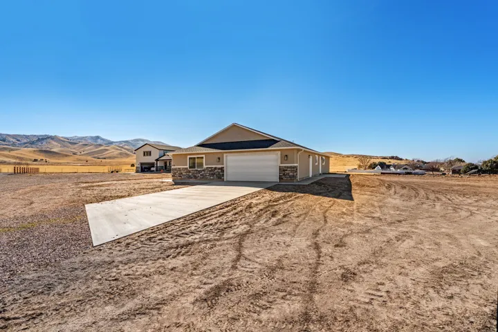 Ranch-style home featuring a mountain view, concrete driveway, stone siding, and a garage