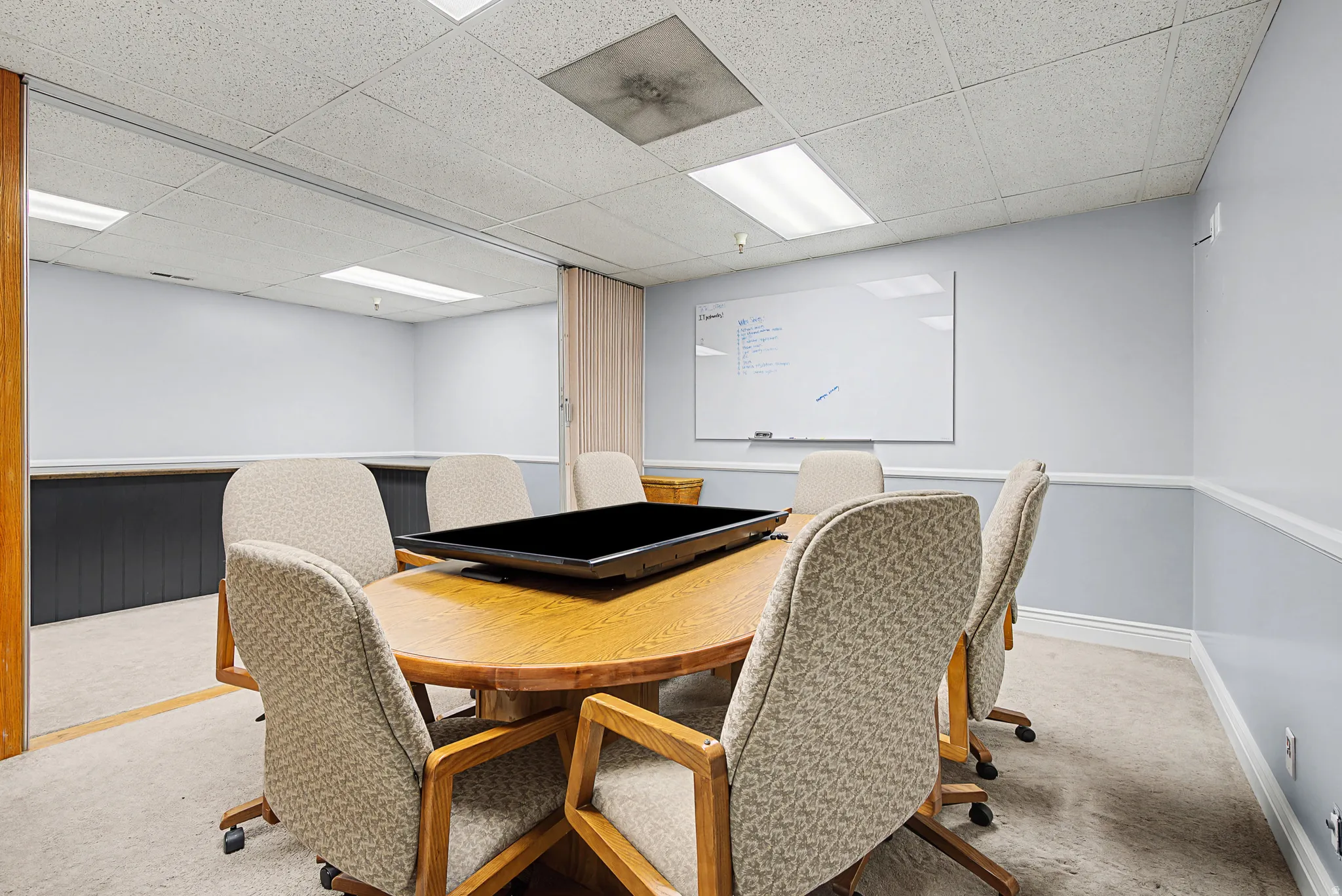 Carpeted dining area featuring a drop ceiling and baseboards