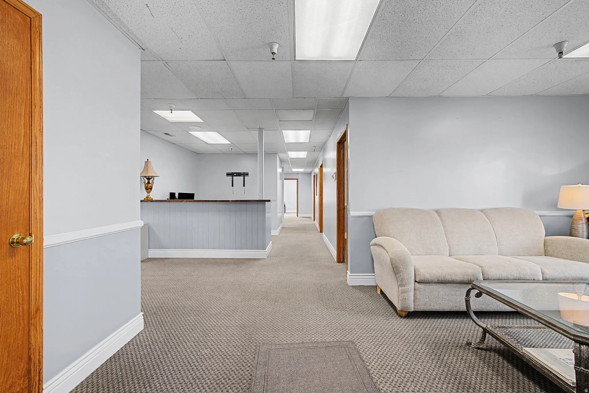 Living room featuring a paneled ceiling and light colored carpet