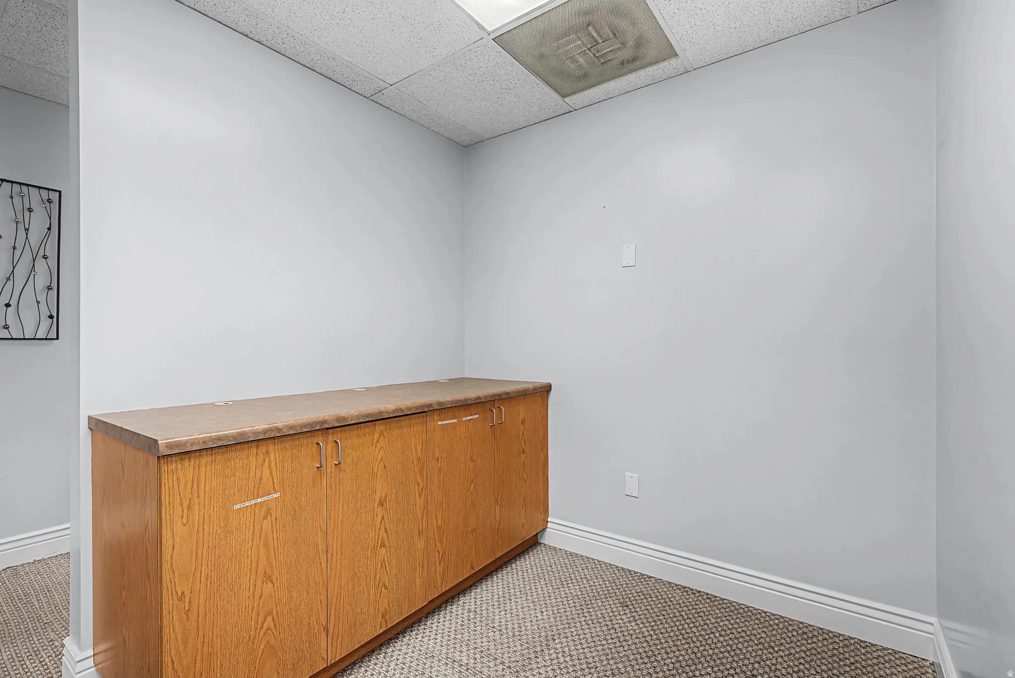 Unfurnished room with a drop ceiling and baseboards