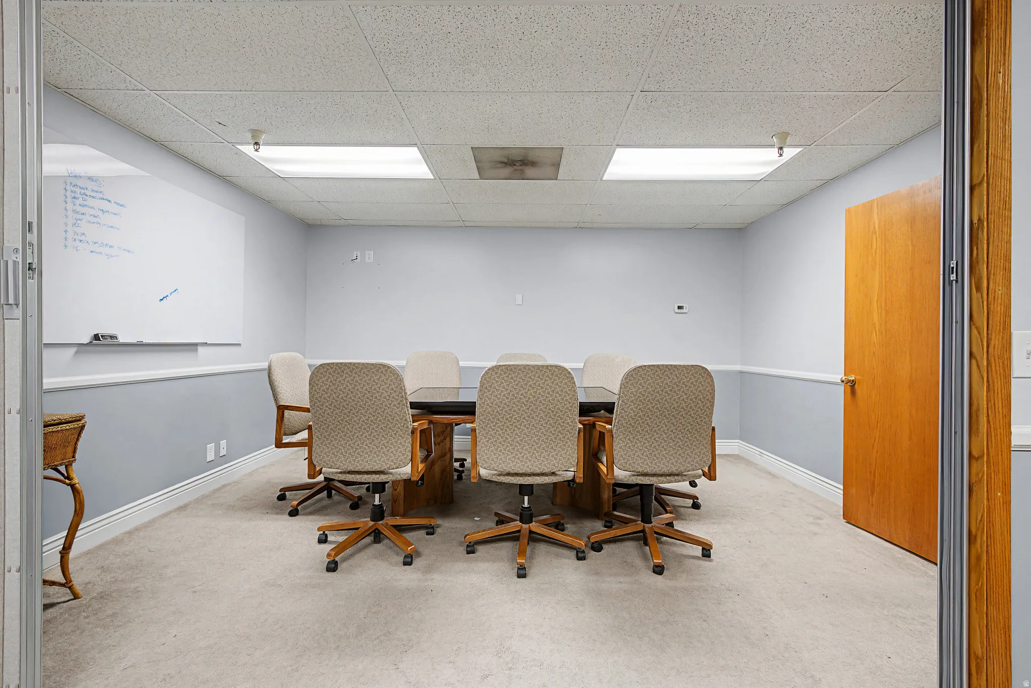 Carpeted office space featuring a paneled ceiling and baseboards
