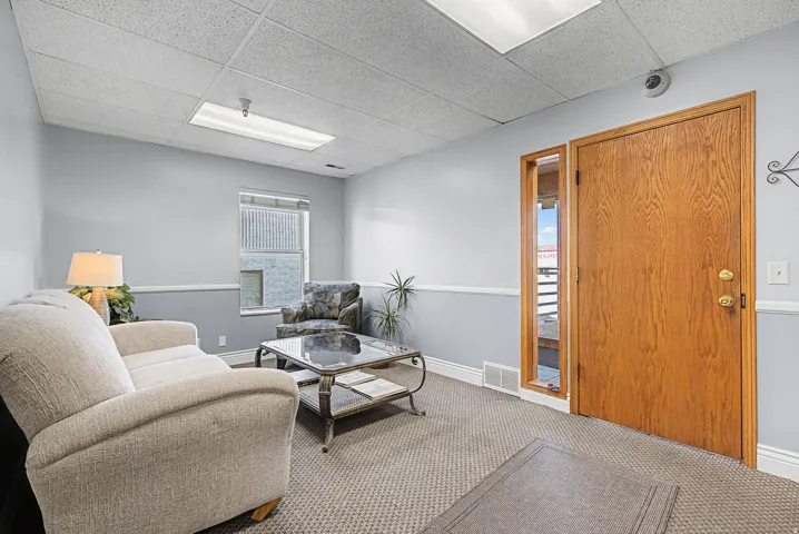 Carpeted living room with a drop ceiling and baseboards
