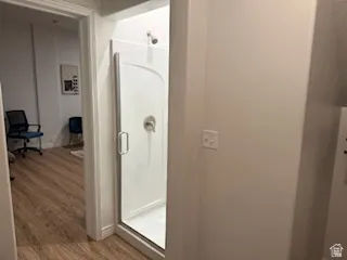 Bathroom featuring a shower stall and wood finished floors