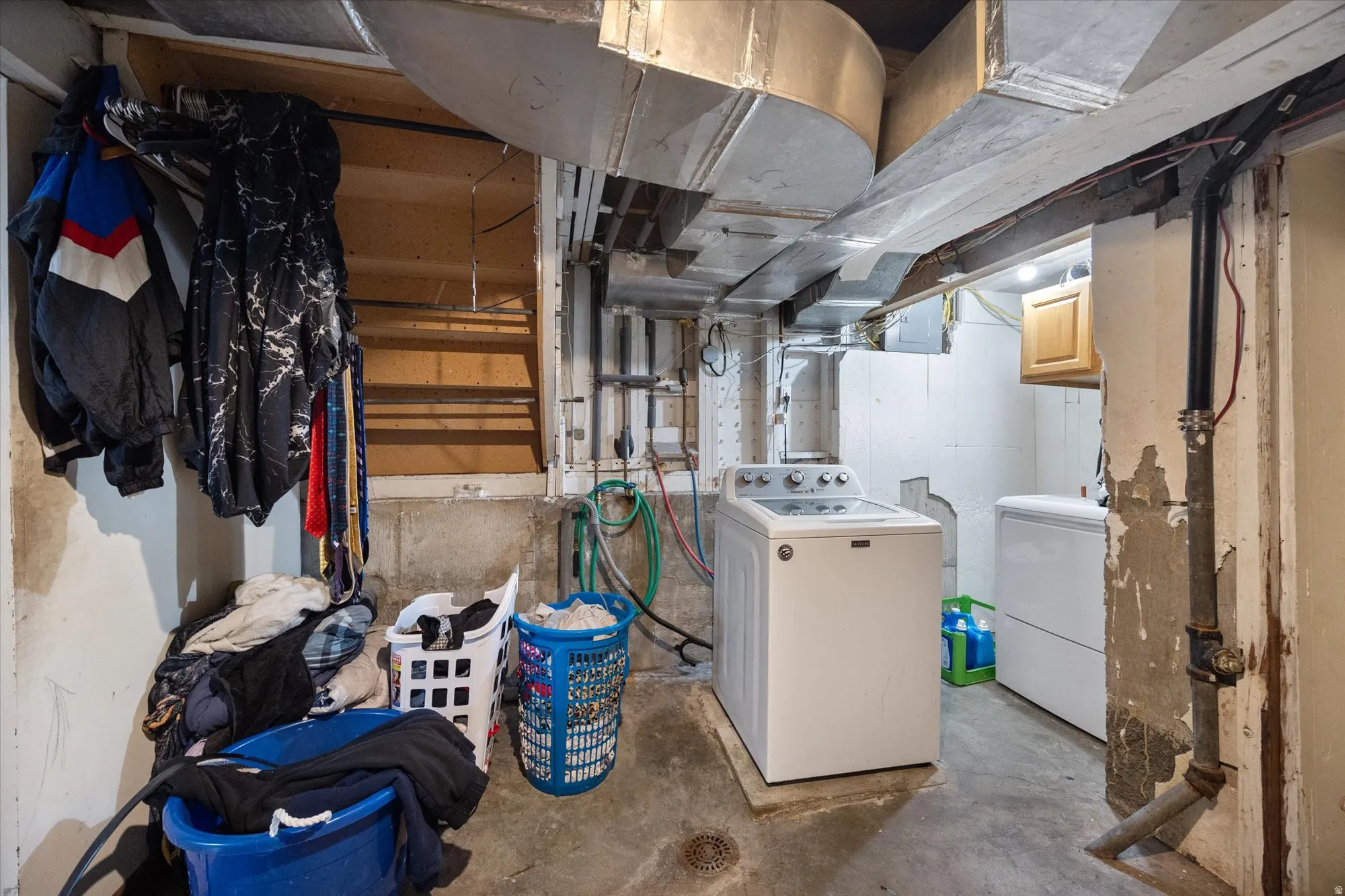 Unfinished basement with separate washer and dryer and electric panel