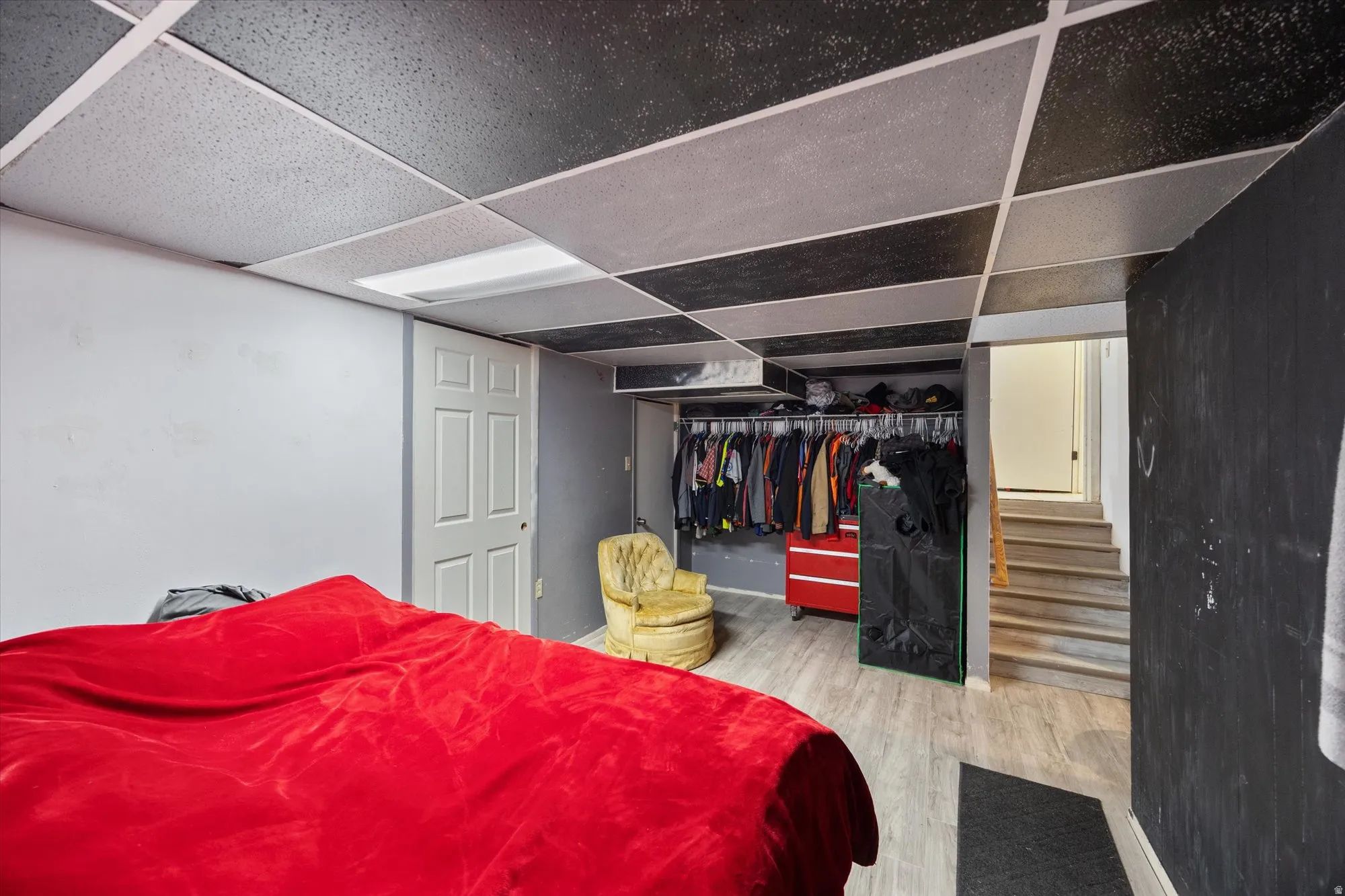 Bedroom featuring a drop ceiling, a closet, and wood finished floors