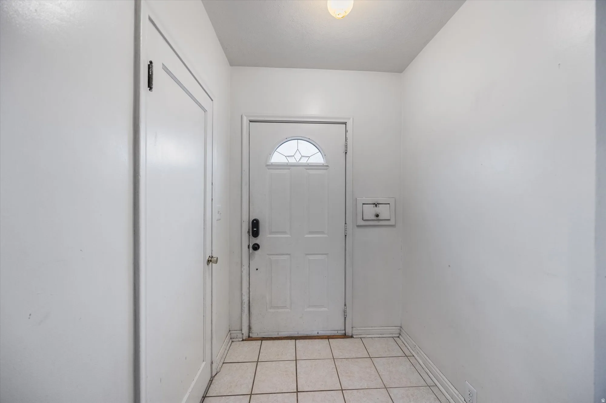 Doorway to outside with baseboards and tile patterned flooring