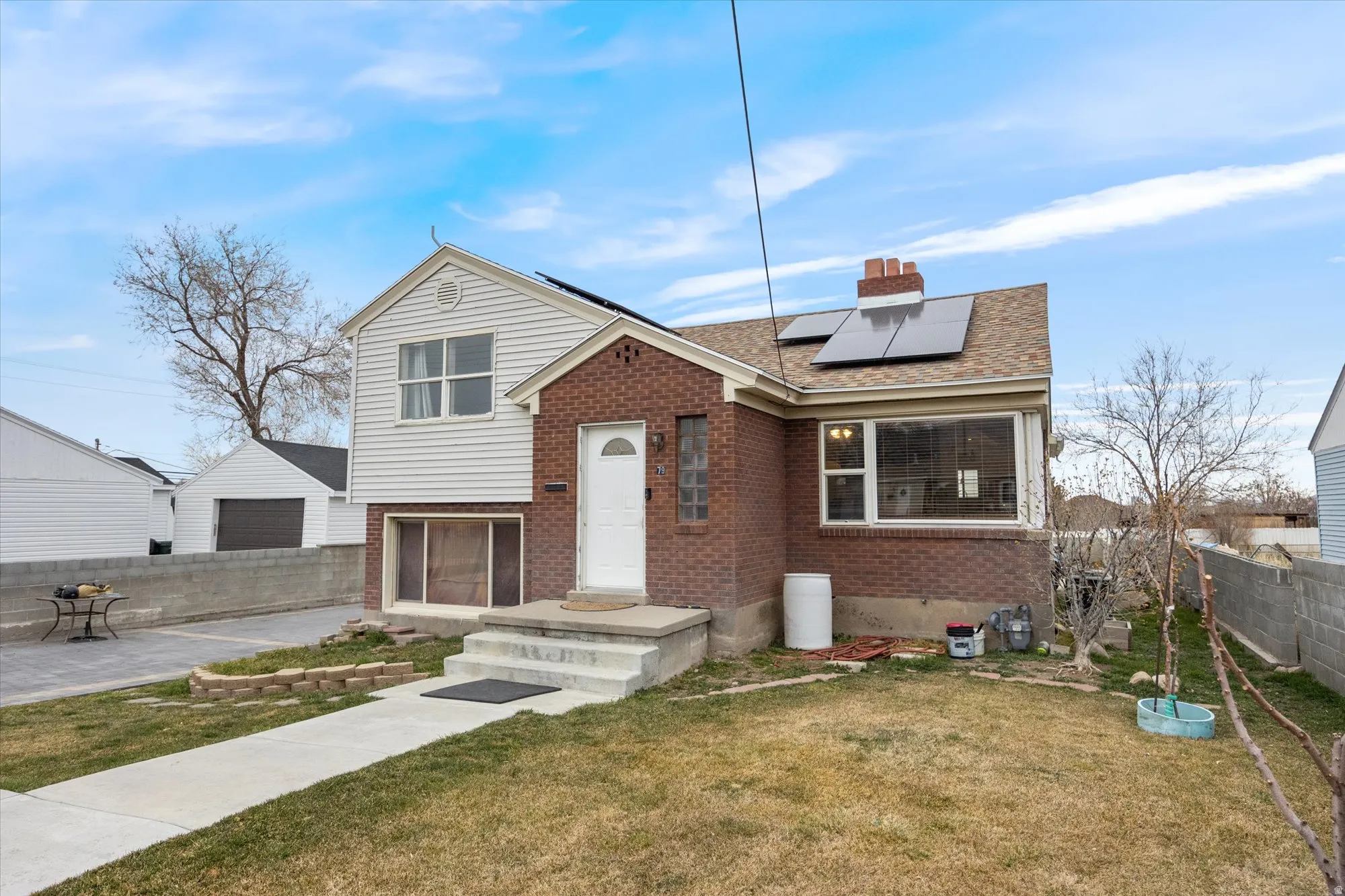Tri-level home with solar panels, brick siding, and a chimney