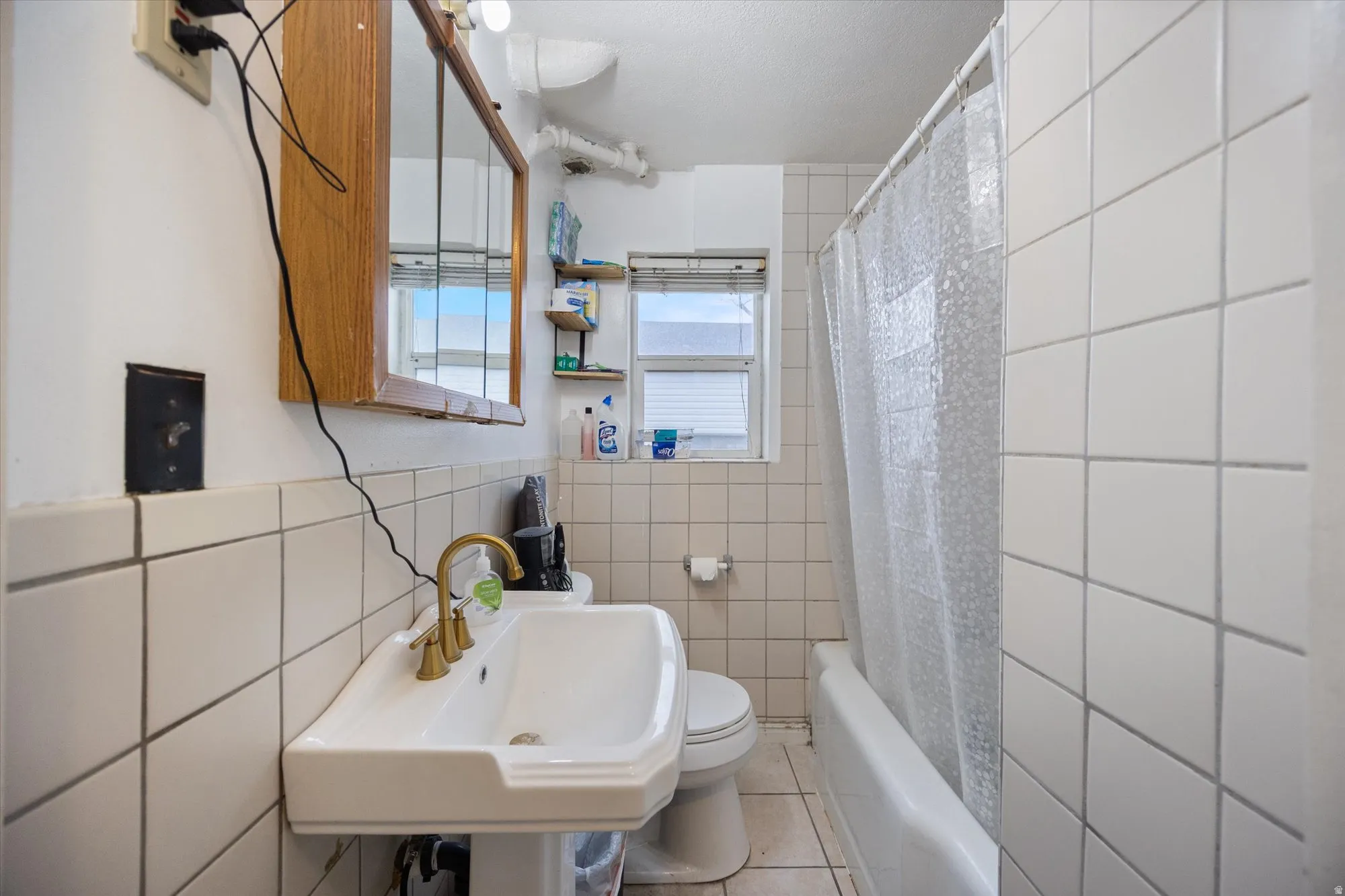Bathroom featuring tile walls, shower / bath combo, and light tile patterned floors